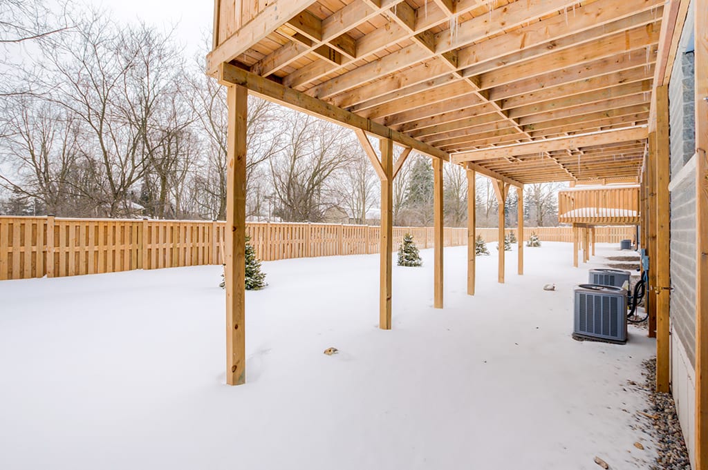 Backyard of House with Wooden Fence Underneath Patio in Winter